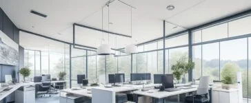 Ein sonnendurchflutetes, modernes Büro mit einem entspannten Entwickler, der lächelnd vor einem großen Bildschirm sitzt, auf dem komplexe Programmieroberflächen schemenhaft zu erkennen sind, während natürliche Holzmöbel und warme Pflanzen eine Atmosphäre von Innovation, Zugänglichkeit und positiver Energie schaffen.