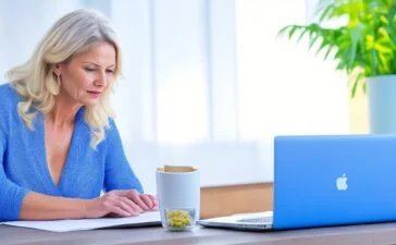 Eine lebendige, sonnendurchflutete Büroszene mit einer entspannten, nachdenklichen Frau vor einem Laptop, die konzentriert ihre persönlichen Daten überprüft, während warme Sonnenstrahlen durch große Fenster fallen und eine Atmosphäre von Zuversicht und aktiver Selbstfürsorge schaffen.