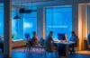 Ein warm beleuchteter, moderner Büroraum, in dem ein dynamisches Tech-Team engagiert an Laptops arbeitet, während natürliches Tageslicht durch große Fenster fällt und die lebhafte Atmosphäre des KI-unterstützten Arbeitsalltags bei Meta einladend einfängt.