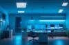 Ein hell erleuchtetes, modernes Büro mit entspannter, fokussierter Person vor einem Laptop, umgeben von warmem Tageslicht und subtilen technischen Details, die eine Atmosphäre von Innovation und digitaler Vernetzung vermitteln.