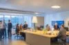 Ein helles, natürlich beleuchtetes Büro mit einem interdisziplinären Team, das in lebendiger Atmosphäre konzentriert lebhaft an kreativen Ideen und Prototypen arbeitet, um gemeinsam durch nutzerzentrierte Produktentdeckung innovative digitale Lösungen zu schaffen und dabei durch warme Farbtöne und freundliche Gesichter eine inspirierende Stimmung voller Vertrauen und Zusammenarbeit ausstrahlt.