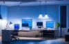 Ein hell erleuchtetes, modernes Büro mit einem konzentrierten IT-Administrator am Laptop, der in natürlichem Tageslicht vor mehreren Bildschirmen sitzt und aufmerksam die Sicherheitseinstellungen einer komplexen SharePoint-Umgebung überprüft, während warme Farben und freundliche Atmosphäre Zuversicht und digitale Verantwortung ausstrahlen.