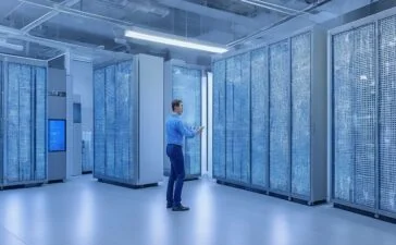In einem modernen, lichtdurchfluteten Serverraum strahlt ein IT-Administrator mit einem warmen Lächeln vor mehreren hochmodernen Monitoren und offenen Serverracks, die mit dezenten LED-Leuchten sanft beleuchtet sind, während die natürliche Tageslichtatmosphäre eine einladende und professionelle Umgebung für innovative Open-Source-Virtualisierung vermittelt.