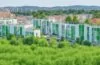 Ein helles, sonnendurchflutetes Außenaufnahme-Panorama eines modernen, modular gestalteten Rechenzentrums in einer urbanen Umgebung, mit klaren Linien, natürlichem Grün im Vordergrund und warmem Tageslicht, das die nachhaltige, zukunftsweisende Technologie und innovative Architektur friedlich und einladend inszeniert.