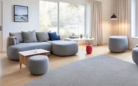 Ein helles, einladendes Wohnzimmer mit sanft durchflutendem Tageslicht, in dem moderne Apple-Smart-Home-Geräte wie HomePod mini und iPad harmonisch in den Alltag eingebunden sind, während eine lächelnde Person entspannt auf dem Sofa sitzt und per Stimme intelligente Beleuchtung und Unterhaltungssystem steuert – eine warme, realistische Szene, die die innovative Verbindung von Technologie und behaglichem Zuhause lebendig einfängt.