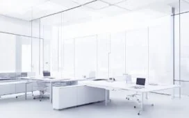 In einem modernen, hell erleuchteten Büro arbeiten mehrere Entwickler entspannt an ihren Laptops, während ein großes, transparentes Whiteboard im Hintergrund komplexe Architekturdiagramme mit modularen Bausteinen zeigt – das Bild strahlt kreative Konzentration, Zusammenarbeit und die warmen Sonnenstrahlen des Vormittags aus.