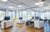 Ein lichtdurchflutetes, modernes Büro mit vielfältigen Berufstätigen in lebendiger Zusammenarbeit, die freundlich lächelnd an Bildschirmen mit KI-gestützten Tools arbeiten – die Atmosphäre strahlt Wärme, Aufbruchsstimmung und den menschlichen Kern der digitalen Arbeitswelt im Wandel aus.