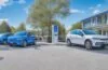 Ein sonnendurchfluteter urbaner Parkplatz mit einem modernen, eleganten BYD Elektro-SUV im Vordergrund, umgeben von entspannten Menschen in leichter Alltagskleidung, die freundliche Gespräche führen, während warmes Tageslicht die hochwertige Lackierung und effiziente, innovative Designs der Fahrzeuge sanft betont – ein Symbol für den dynamischen Aufbruch und die Zukunft der Elektromobilität in Europa.