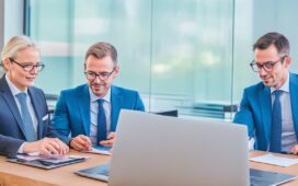 Helle, freundliche Büroszene mit mehreren konzentrierten Fachleuten in moderner Geschäftskleidung, die lebhaft an digitalen Geräten arbeiten und gemeinsam Strategien zur IT-Sicherheit und Compliance im Finanzsektor besprechen, eingefangen in warmem, natürlichem Licht mit realistischen Details und einem klaren, einladenden Ambiente.