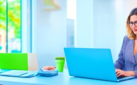 Eine warme, helle Büroaufnahme zeigt eine konzentrierte junge Frau vor einem Laptop mit geöffnetem E-Mail-Postfach, umgeben von natürlichem Tageslicht und modernen Details, die digitale Sicherheit und Wachsamkeit im Alltag einfühlsam vermitteln.