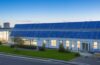 Modernes Rechenzentrum mit großen batteriebetriebenen Energiespeichern in hellem, natürlich beleuchtetem Serverraum, warmes Sonnenlicht strömt durch Fenster und betont die technische Präzision sowie die nachhaltige Zukunftstechnologie in einer einladenden, freundlichen Atmosphäre.