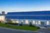 Modernes Rechenzentrum mit großen batteriebetriebenen Energiespeichern in hellem, natürlich beleuchtetem Serverraum, warmes Sonnenlicht strömt durch Fenster und betont die technische Präzision sowie die nachhaltige Zukunftstechnologie in einer einladenden, freundlichen Atmosphäre.