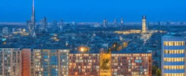 Helles, stimmungsvolles Editorial-Foto eines modernen Rechenzentrums im urbanen Frankfurter Umfeld bei sanftem Tageslicht, das durch große Panoramafenster flutet, mit Fokus auf technische Details wie Serverracks und Kabelbündel, während im Hintergrund die Silhouette der Mainmetropole warm leuchtend zu erkennen ist und so die Spannung zwischen digitalem Fortschritt und Energieherausforderung eindrucksvoll vermittelt wird.