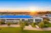 Ein freundliches, lichtdurchflutetes Panorama eines modernen Rechenzentrums-Campus bei Morgenlicht, mit glänzenden Glasfassaden, grünen Solarpaneelen auf den Dächern und einem im Vordergrund entspannten Team von IT-Experten in legerer Business-Kleidung, das konzentriert am Tablet über innovative Cloud- und KI-Technologien diskutiert, wodurch ein Bild nachhaltiger Hightech-Entwicklung und zukunftsweisender Investitionen entsteht.