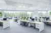 Ein lichtdurchflutetes modernes Büro mit motivierten IT-Fachkräften in entspannter, freundlicher Atmosphäre, die konzentriert und zugleich kollegial an Laptops und digitalen Whiteboards zusammenarbeiten, während warme Sonnenstrahlen das Szenenbild mit natürlichem Glanz und lebendiger Energie erfüllen.