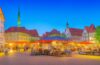 Ein sonnendurchfluteter, belebter Marktplatz in einer niedersächsischen Stadt, auf dem moderne Sicherheitskameras diskret an Laternenmasten montiert sind, während freundliche Passanten in entspannter Atmosphäre ihrem Alltag nachgehen und die warme, natürliche Lichtstimmung Vertrauen und Dialogbereitschaft zwischen Technologie und Gesellschaft symbolisiert.