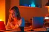 In einem hell erleuchteten, modernen Arbeitszimmer sitzt eine junge Frau entspannt vor einem Laptop, umgeben von warmem Tageslicht, während dezent digitale Symbole für Datenschutz und Künstliche Intelligenz sanft im Hintergrund schimmern und so die Balance zwischen Technologie und Privatsphäre bildhaft vermitteln.
