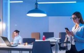 In einem hell erleuchteten, modernen Büro sitzt eine junge Frau konzentriert vor ihrem Smartphone, umgeben von warmem Tageslicht und dezentem Grünpflanzen-Flair, während sie achtsam ihre App-Berechtigungen überprüft – ein Sinnbild für digitale Vorsicht und aktive Cybersicherheit im Alltag.