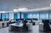 Ein hell erleuchtetes, modernes Büro mit entspannten Mitarbeitenden unterschiedlichen Alters und Hintergrunds, die in offener Kommunikation um einen Laptop gruppiert sind und gemeinsam konzentriert an der Integration neuer Technologie arbeiten, wobei warmes Tageslicht sanft die freundliche Arbeitsatmosphäre durchflutet.