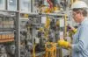 Helle, realistische Aufnahme eines technikaffinen Ingenieurs in moderner Rechenzentrumsumgebung, der konzentriert an hochkomplexen Schaltanlagen mit integrierter Sensorik arbeitet, umgeben von warmem Tageslicht, das eine freundliche und sichere Atmosphäre für innovative, unterbrechungsfreie Wartungsprozesse erzeugt.