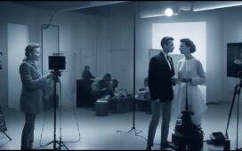 Ein hell erleuchtetes, modernes Studio mit einer stilvoll inszenierten jungen Frau, die selbstbewusst in die Kamera lächelt – ihr Aussehen wirkt zeitgemäß und leicht futuristisch, während warmes Tageslicht ihre Gesichtszüge sanft betont und eine freundliche, einladende Atmosphäre schafft, die Innovation und digitale Nähe verkörpert.