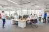 Ein lebendiges, sonnendurchflutetes Büro mit jungen, engagierten Entwicklerteams in lebhafter Zusammenarbeit über Laptops und Skizzen, umgeben von moderner Technik und kreativen Whiteboards, die eine inspirierende Atmosphäre digitaler Innovation und gemeinsamer Ideenentwicklung ausstrahlt.