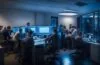 Ein hell erleuchtetes, zeitgemäßes Büro mit einem konzentrierten Team aus vielfältigen Fachleuten, die an Bildschirmen datenintensive Softwarelösungen besprechen, während warme Sonnenstrahlen durch große Fenster fallen und eine Atmosphäre von Vertrauen, Verantwortung und zukunftsorientierter Zusammenarbeit schaffen.