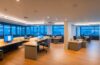 Ein warm beleuchtetes, modernes Büro mit einem nachdenklichen asiatisch aussehenden IT-Experten vor mehreren Bildschirmen, die Datenströme und KI-Symbole zeigen, eingefangen in einem klaren, natürlichen Licht, das die Atmosphäre von Transparenz und technologischer Verantwortung eindrucksvoll vermittelt.