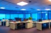 Ein hell ausgeleuchtetes, modernes Büro mit warmem Tageslicht, in dem ein konzentrierter Entwickler vor mehreren Bildschirmen mit komplexen Codezeilen sitzt, umgeben von Notizen und technischer Ausstattung, die die engagierte Open-Source-Community und ihre Herausforderungen gegen unsichtbare Cybergefahren lebendig und nahbar zeigt.