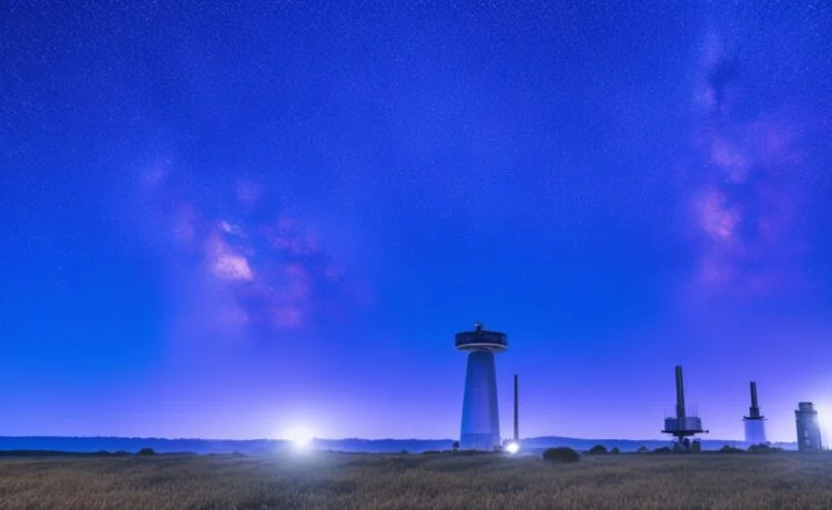 Strahlendes, natürlich beleuchtetes Foto einer modernen Bodenstation mit DE-CIX-Ingenieuren bei der Arbeit, im Hintergrund klar sichtbare LEO-Satelliten am blauen Himmel und sanfte Sonnenstrahlen, die Wärme und die zukunftsweisende Partnerschaft zwischen Netzwerk- und Raumfahrttechnologie einladend vermitteln.