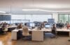 In einem hell erleuchteten, modernen Büro sitzt ein Team aus vielseitigen Fachkräften konzentriert um einen großen Tisch, lebhaft im Austausch über digitale Strategien zur Optimierung von KI-Workflows, während durch große Fenster warmes Tageslicht fällt und eine freundliche Atmosphäre voller Innovationsgeist und Zusammenarbeit schafft.