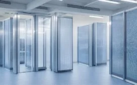 In einem modernen Rechenzentrum strahlt warmes Tageslicht durch große Fenster, während technikaffine Fachleute konzentriert an hochmodernen Serverracks arbeiten und so den lebendigen Geist von Innovation und nachhaltigem Fortschritt in der digitalen Infrastruktur verkörpern.