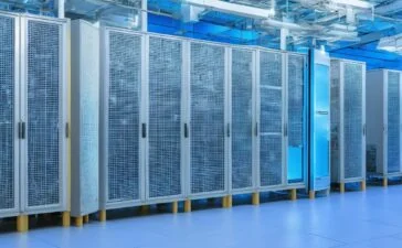 Ein warm beleuchtetes, modernes Rechenzentrum mit eleganten Serverracks, in dem ein Team konzentriert an der Schnittstelle zwischen klassischen Computern und einer futuristischen Quantenhardware arbeitet, während sanftes Tageslicht durch große Fenster fällt und die innovative, harmonische Symbiose von Technologie und Menschlichkeit unterstreicht.