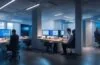 In einem hell erleuchteten, modernen Büro sitzen engagierte Kreative mit strahlenden Gesichtern vor großen Bildschirmen, während sie in einem inspirierenden Austausch über digitale Designs und Nutzererlebnisse stehen, umgeben von natürlichen Lichtreflexen und warmen Holztönen, die eine offene, optimistische Atmosphäre schaffen.