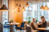 Ein warm beleuchtetes, modernes Café-Interieur, in dem eine lächelnde junge Frau entspannt mit ihrem Smartphone kontaktlos bezahlt, während im Hintergrund unscharf stilvoll gestaltete, digitale Finanzgrafiken auf einem transparenten Bildschirm dezent und elegant andeuten, wie Blockchain-Technologie Sicherheit und Innovation im Alltag verbindet.
