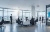 In einem modernen, lichtdurchfluteten Büro strahlen engagierte Fachleute bei einem interdisziplinären Meeting Wärme und Zuversicht aus, während auf einem großen Bildschirm komplexe, vernetzte Datenströme als leuchtende Graphen symbolisch zusammengeführt werden – Sinnbild für die harmonische Vereinigung plattformübergreifender KI-Standards in einer offenen, kooperativen Arbeitsatmosphäre.