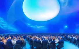 Ein hell erleuchteter, moderner Konferenzraum mit internationalen Experten unterschiedlicher Herkunft, die in entspannter Atmosphäre angeregt über globale KI-Regeln diskutieren, während sanftes Tageslicht durch große Fenster fällt und warme Holztöne den Raum einladend gestalten.