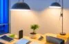 Ein strahlendes, natürlich beleuchtetes Büro mit einem lächelnden Entwickler vor einem modernen iPhone, das lebendig das neue, dynamische iOS-26-Interface zeigt, umgeben von dezent eingesetzter, warmer Raumbeleuchtung und subtilen technologischen Details, die Innovation und Benutzerfreundlichkeit ausstrahlen.