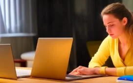 Eine moderne Büroszene in warmem Tageslicht, in der eine nachdenkliche junge Frau konzentriert auf ihren Laptop schaut, während im Hintergrund dezent ein Kollege im Gespräch ist – symbolisch für den sensiblen Umgang mit digitalen Nachrichten und den Schutz vor cleveren Cyberangriffen durch KI.