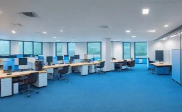 Ein hell erleuchtetes, modernes Büro mit entspannt lächelnden Menschen, die an einem großen Bildschirm gemeinsam ein übersichtliches, ansprechendes E-Mail-Layout mit klaren Farben und interaktiven Elementen diskutieren – dabei strahlt warmes Tageslicht durch große Fenster und schafft eine freundliche, einladende Atmosphäre voller Produktivität und Kreativität.