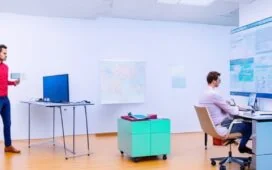 In einem hell erleuchteten, modernen Büro lächelt ein Softwareentwickler entspannt beim fokussierten Arbeiten am Laptop, umgeben von Notizen und einem übersichtlichen Whiteboard mit schematischen Skizzen – ein einladendes Bild für innovative Testing-Methoden jenseits von Mocking.
