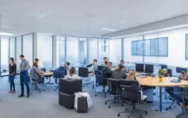 Ein hell erleuchtetes, modernes Büro mit einem kleinen Team von Softwareentwicklern in konzentrierter, aber freundlicher Atmosphäre, die gemeinsam an einem übersichtlichen Whiteboard komplexe Abläufe erklären und die Vorteile einer vereinfachten monolithischen Softwarearchitektur besprechen, wobei warmes Tageslicht durch große Fenster fällt und eine produktive sowie harmonische Stimmung schafft.