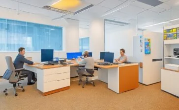 Ein helles, einladendes Büro mit warmem Tageslicht, in dem eine lächelnde Person vor einem modernen Computer sitzt und konzentriert die Google-Suchseite nutzt, umgeben von dezent digital wirkenden Elementen, die den Dialog zwischen traditioneller Suche und KI-Technologie subtil symbolisieren.