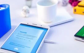 Ein sonnenbeschienener, moderner Arbeitsplatz mit einem entspannt lächelnden Menschen, der auf seinem Android-Smartphone in den hellen, klaren Einstellungen den Private-DNS-Modus aktiviert, umgeben von warmem Tageslicht und natürlichen Details, die digitale Sicherheit und vertrauliche Technik harmonisch verbinden.