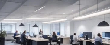 Ein hell erleuchtetes, modernes Entwicklerbüro mit freundlichen Menschen, die konzentriert an Laptops arbeiten, lebendige Gespräche führen und innovative Softwarelösungen skizzieren – strahlende Tageslichtstimmung mit warmen Holztönen, klaren Linien und einer inspirierenden Atmosphäre, die Fortschritt und kreative Zusammenarbeit in der Webentwicklung verkörpert.