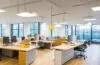 Ein warm beleuchtetes, modernes Büro mit einem konzentrierten Mitarbeiter vor mehreren Bildschirmen, die Daten und Online-Shopping-Statistiken in natürlichem Tageslicht zeigen – Sinnbild für die KI-gesteuerte dynamische Preisgestaltung im E-Commerce.