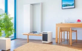 Ein helles, einladendes Wohnzimmer mit natürlichem Tageslicht, in dem ein moderner TP-Link-Router auf einem stilvollen Holztisch steht, umgeben von entspannten Menschen aller Altersgruppen, die sorglos über ihre digitalen Geräte lächeln – symbolisch für das sensible Gleichgewicht zwischen Komfort und der unsichtbaren Herausforderung der Netzwerksicherheit zu Hause.