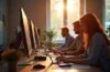In einem hell erleuchteten, modernen Kreativstudio arbeiten Menschen konzentriert und lächelnd gemeinsam an digitalen Bildschirmen, während sanftes Tageslicht durch große Fenster fällt und eine warme, inspirierende Atmosphäre schafft, die den harmonischen Austausch zwischen Mensch und KI in kreativen Prozessen symbolisiert.