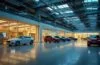 Ein hell erleuchtetes, modernes Industriegebäude von Jaguar Land Rover mit klaren Details, in warmes Sonnenlicht getaucht, während konzentrierte Fachleute in smarter Business-Kleidung an vernetzten Computern arbeiten, die angespannte, aber zuversichtliche Atmosphäre einer digitalen Krisenreaktion vermitteln.