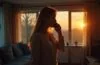 Eine helle, natürlich beleuchtete Szene in einem modernen Wohnzimmer, in der eine besorgte Frau mit aufmerksamer Miene telefoniert, während sanftes Sonnenlicht durch große Fenster fällt und eine warme, vertrauensvolle Atmosphäre schafft, die zugleich die unterschwellige Anspannung vor einem möglichen Betrugsanruf spürbar macht.